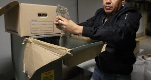 un hombre colocando credenciales para votar sin validez en maquina trituradora