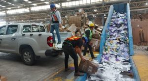 tres hombres subiendo cajas con papel a una camioneta