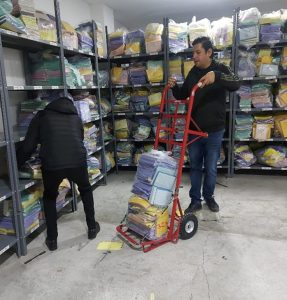 un hombre sosteniendo un carro con dos ruedas y material encima