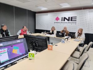 personas sentadas en un salón alrededor de una mesa rectangular