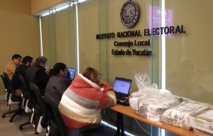 personas sentadas frente a una pared de cristal con letras negras