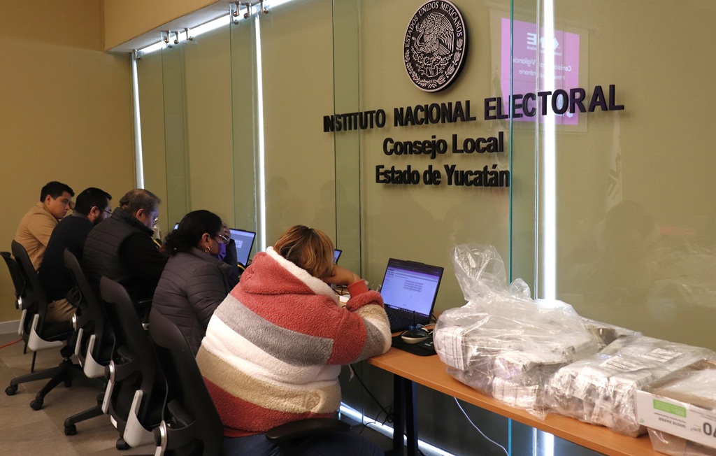 personas sentadas frente a una pared de cristal con letras negras