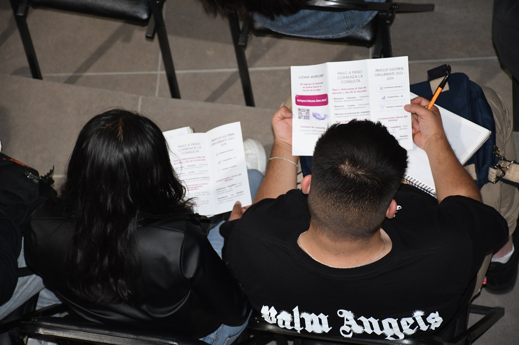 dos estudiantes leyendo el folleto del sistema de la estadística electoral del INE