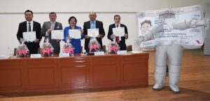 cuatro hombres y una mujer sosteniendo un documento a lado una botarga de credencial