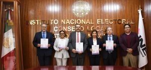 tres hombres y dos mujeres de pie sosteniendo un reconocimiento