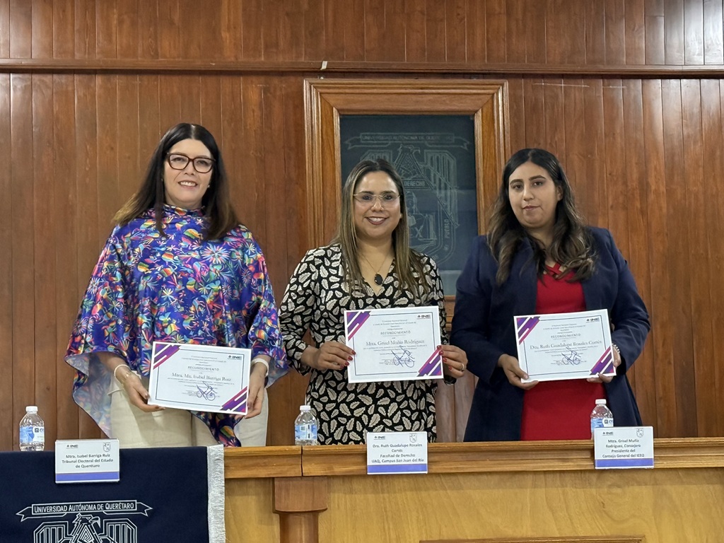 tres mujeres de pie sosteniendo, cada una, un reconocimiento