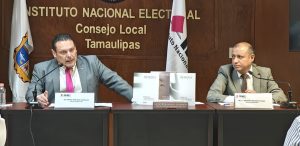 Dos hombres sentados frente a dos micrófonos en medio tres libros