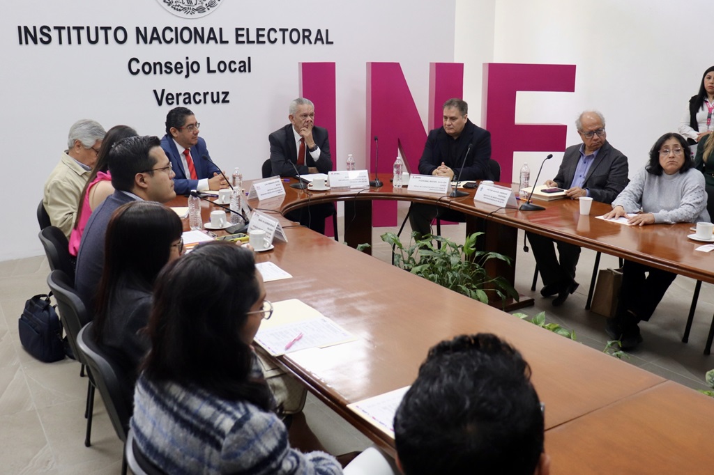 Once personas reunidas sentadas detrás de una mesa larga