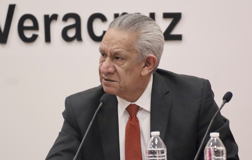 hombre de pelo cano vestido de traje a hablando a través de un micrófono.