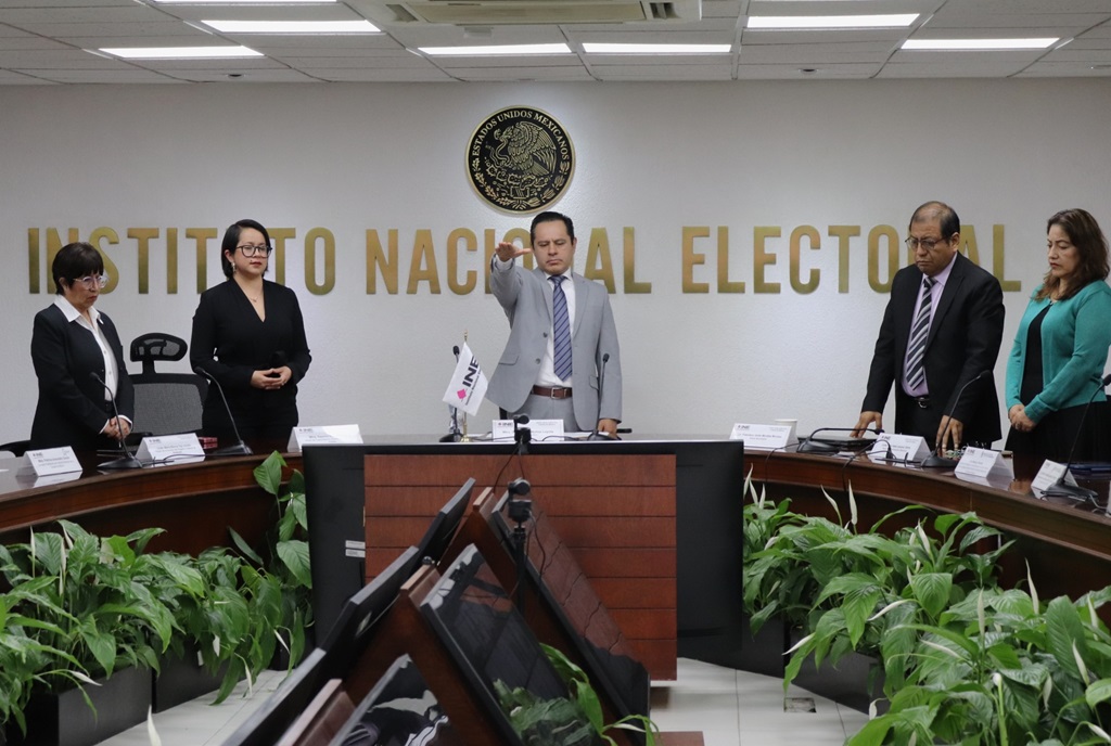 Cinco personas reunidas de pie detrás de una mesa alargada