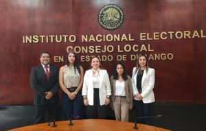 cuatro mujeres y un hombre de pie frente a letras color dorado