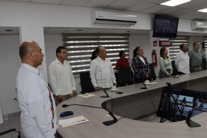 varias personas de pie alrededor de una mesa con micrófonos