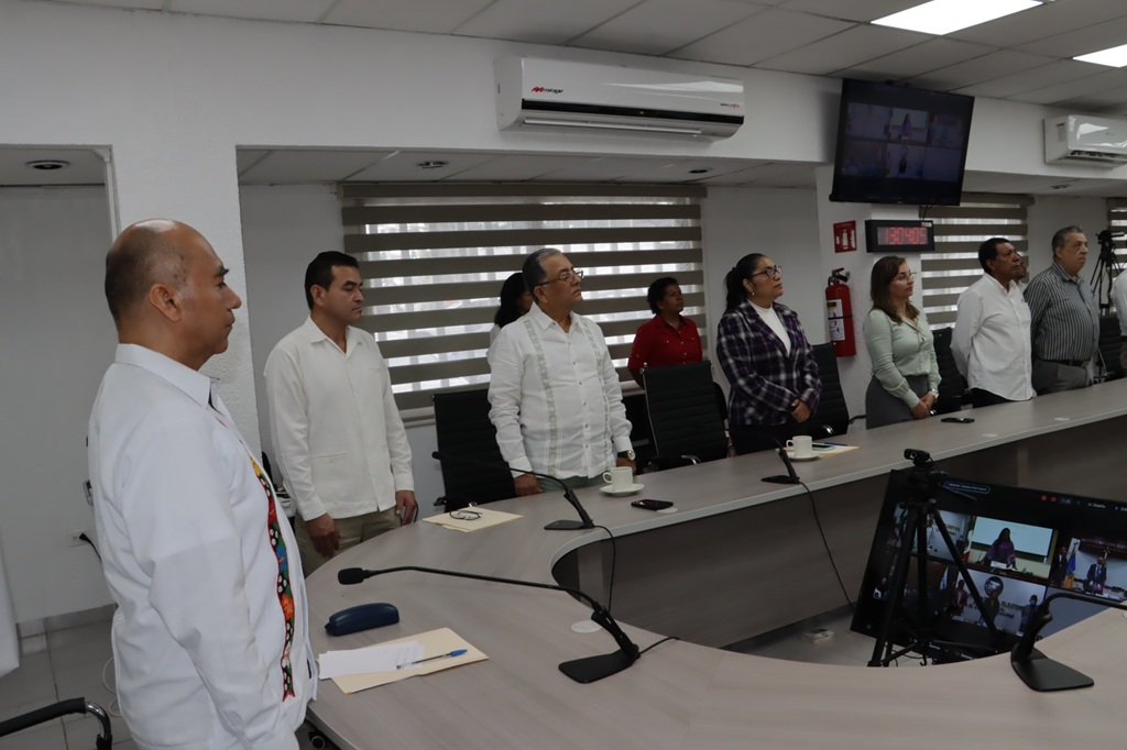 varias personas de pie alrededor de una mesa con micrófonos