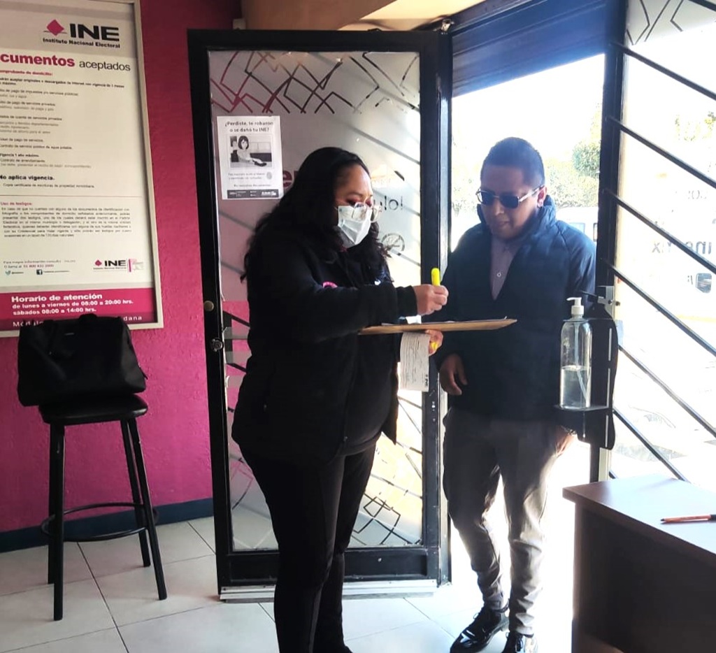 una mujer con cubrebocas recibiendo a un hombre