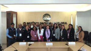 varias personas de pie frente a una mesa rectangular