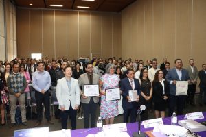 Más de treinta personas reunidas de pie, tres de ellas sostienen un certificado de clausura