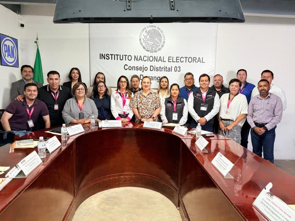 Varias personas de pie alrededor de una mesa ovalada