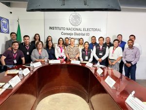 Varias personas de pie alrededor de una mesa ovalada