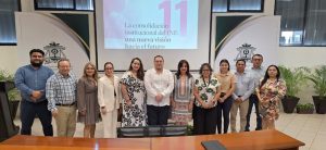 Doce personas de pie reunidas detrás de una mesa larga