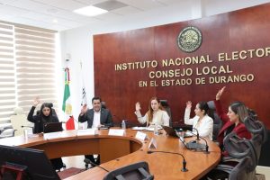 Cuatro personas sentadas votando a mano alzada