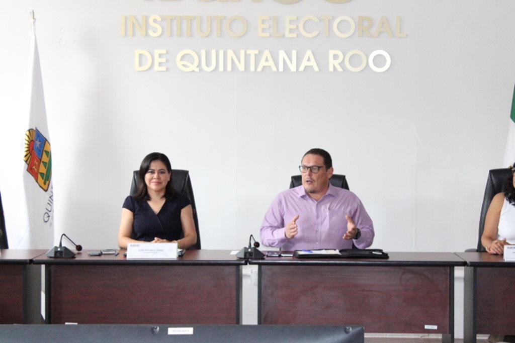 Una mujer y un hombre sentados frente a una mesa con micrófonos