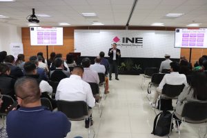 varias personas sentadas escuchando a un hombre que habla