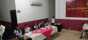 varias personas menores de edad sentadas frente a una mesa con mantel blanco y rosa