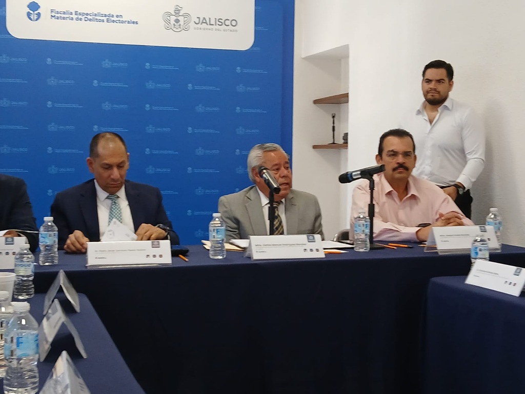 Tres hombres sentados frente a una mesa con micrófono