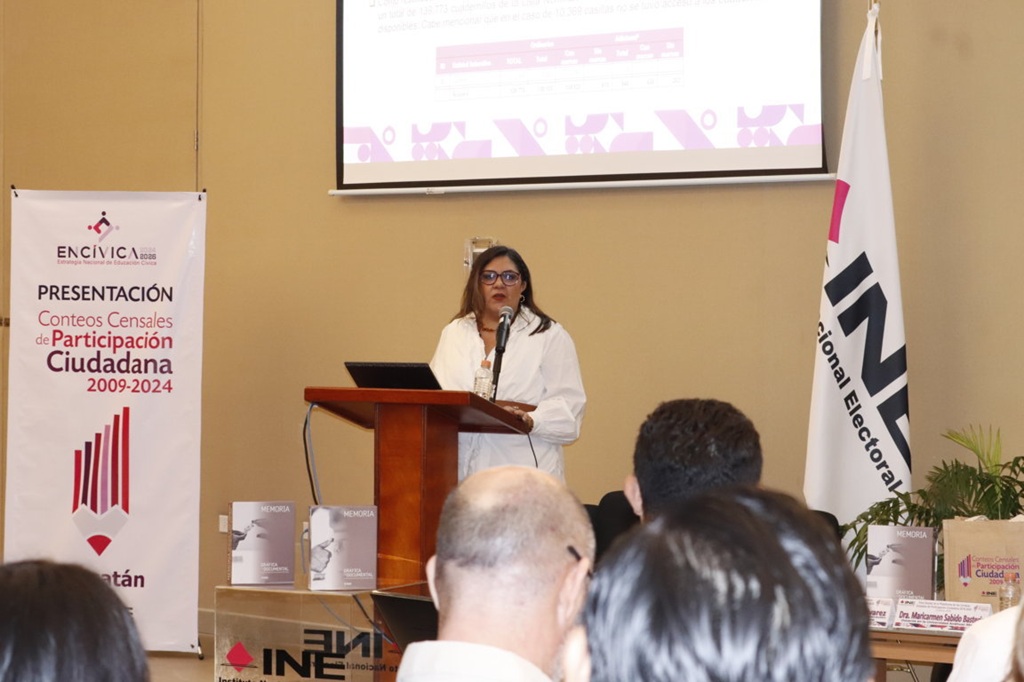 mujer vestida de blanco de pie frente a personas sentadas