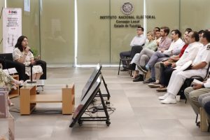 Una mujer sentada frente a personas vestidas de blanco