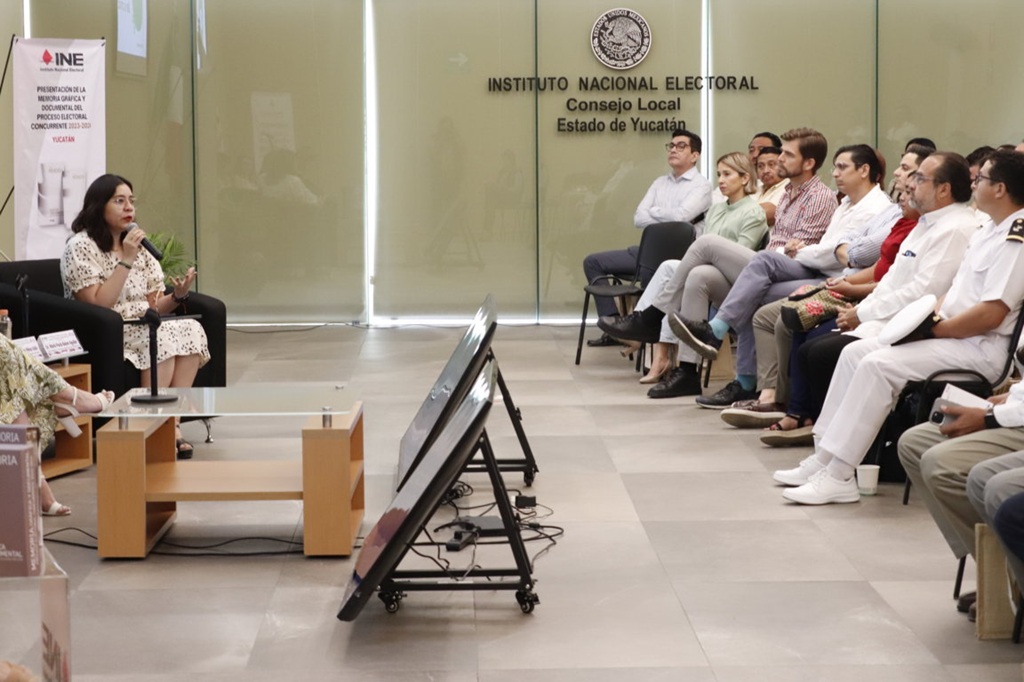 Una mujer sentada frente a personas vestidas de blanco
