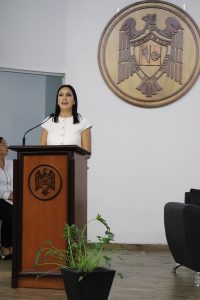 Mujer de pie hablando por micrófono de un atril