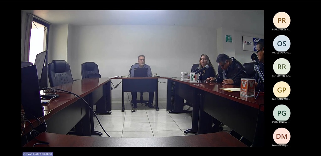 Cuatro personas sentadas detrás de una mesa larga hablando a través de micrófonos.