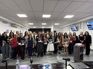 Más de veinte personas de pie, reunidas para la toma de una fotografía.