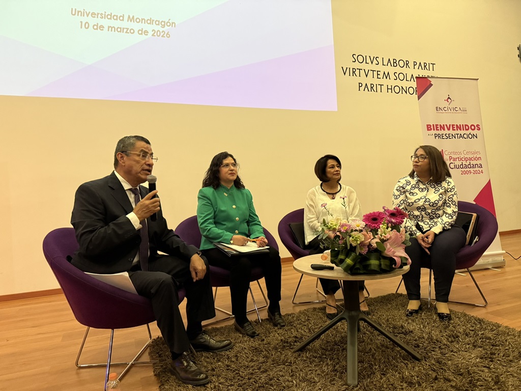 Cuatro personas sentadas reunidas detrás de una mesa redonda 