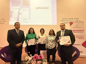 Cinco personas de pie reunidas, dos de ellas sosteniendo un reconocimiento