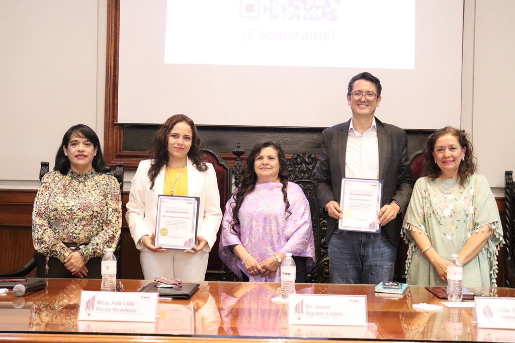 cuatro mujeres y un hombre de pie frente a una mesa