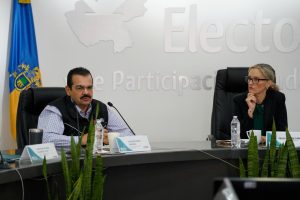 una mujer y un hombre sentados frente a micrófonos