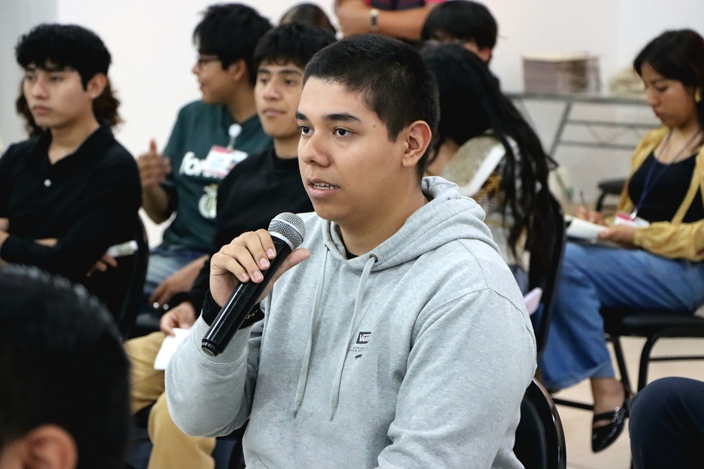 Hombre joven vestido de gris hablando a través de un micrófono