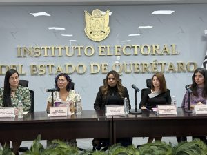 cinco mujeres sentadas frente a micrófonos
