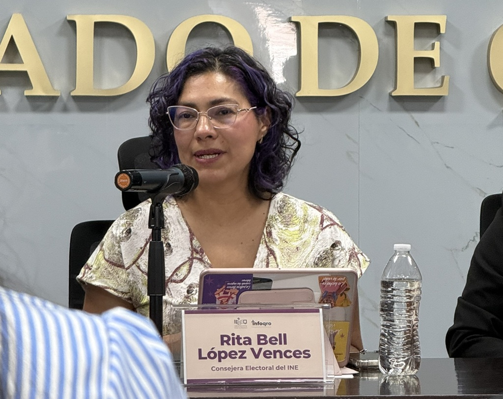 una mujer sentada de lentes hablando frente a un micrófono