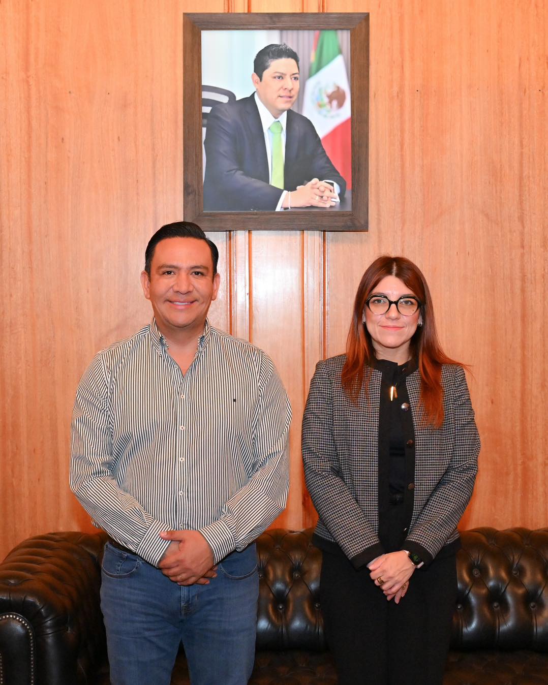 una mujer y un hombre de pie bajo una fotografía