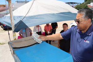 Hombre vestido de playera azul sosteniendo varias credenciales para votar para su destrucción