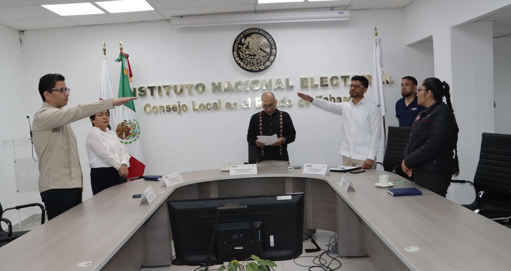 cuatro personas de pie alrededor de una mesa rectangular