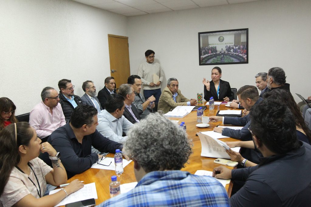 Personas participantes sentadas en la mesa dialogando.