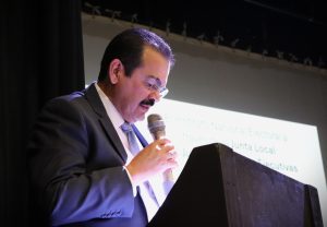 un hombre mirando hacia abajo y hablando a través de un micrófono