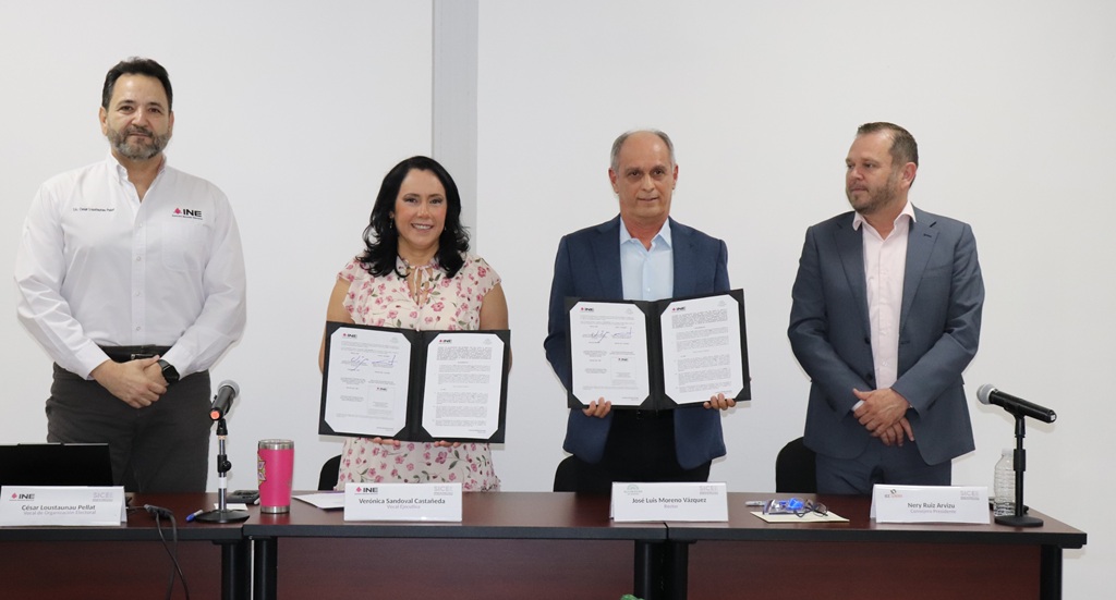 Una mujer y tres hombres de pie mientras sostienen dos carpetas negras con documentos