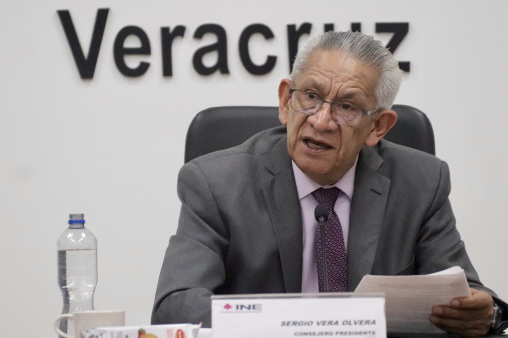 un hombre de pelo cano y lentes, sentado.