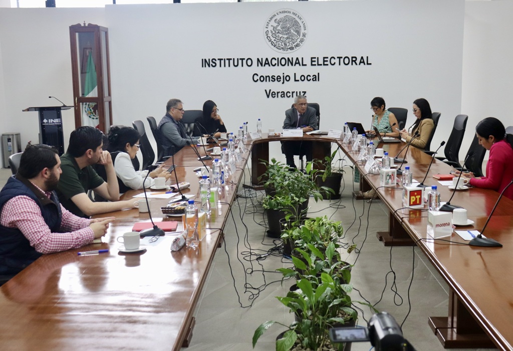 varias personas sentadas alrededor de una mesa ovalada de madera