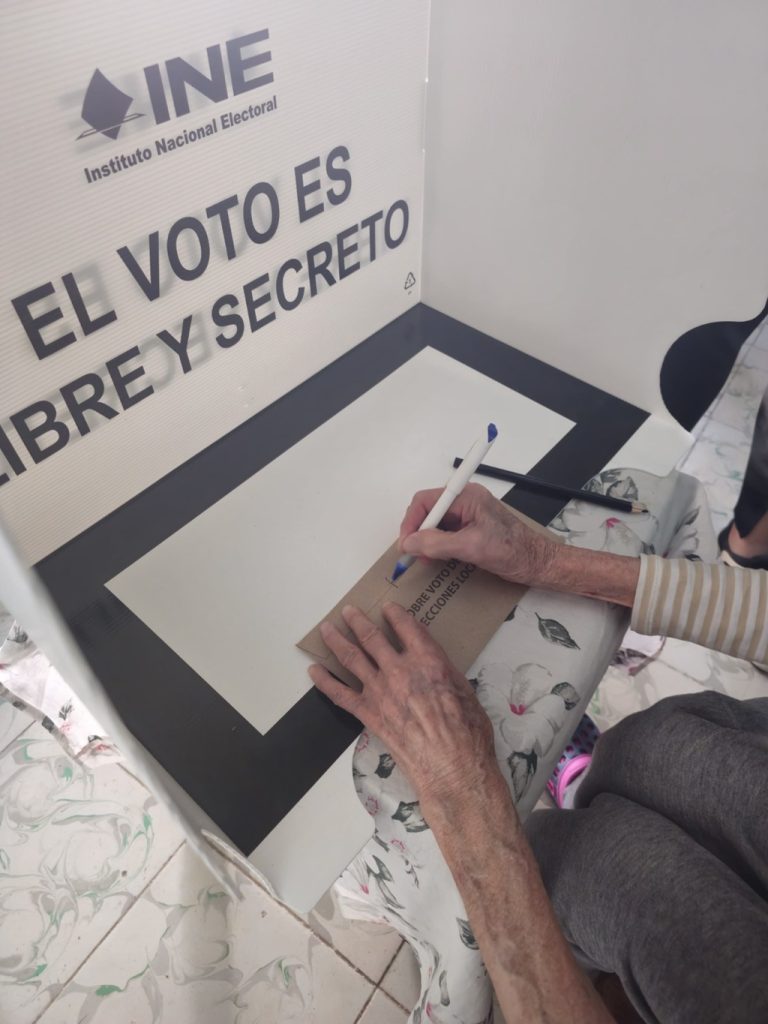 una persona adulta mayor ejerciendo el voto en una urna